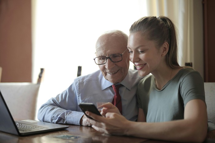 grandfather and family member looking at pricing on phone and computer