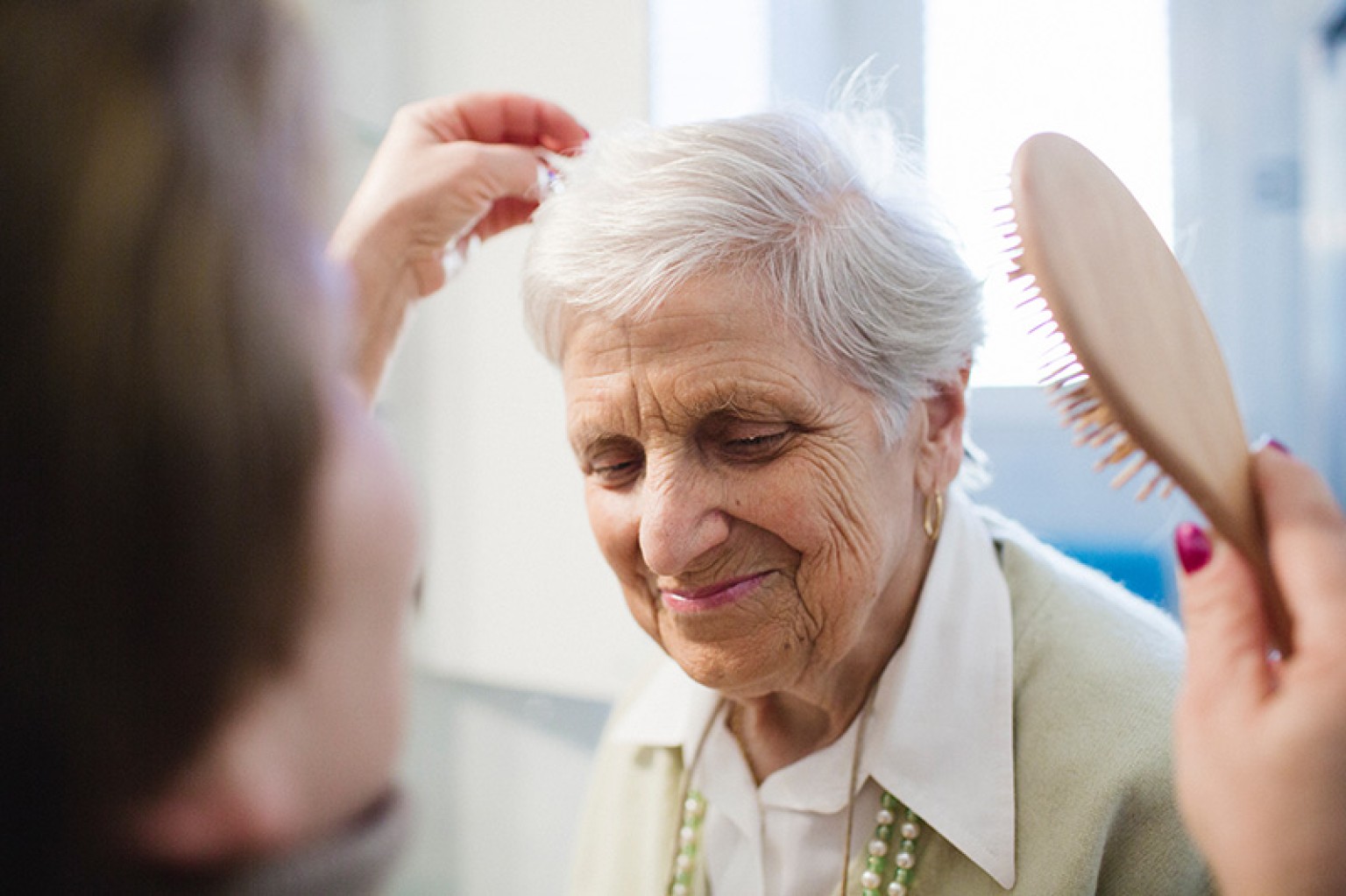 caregiver helping a woman brush her hair